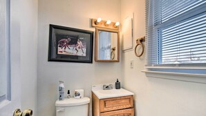 A bathroom with a toilet, a sink, a mirror, and a framed picture on the wall.