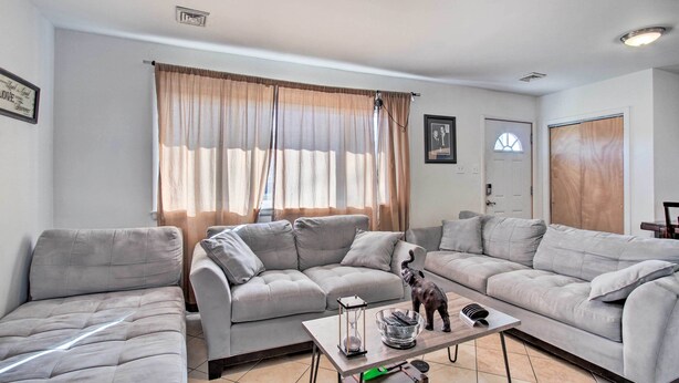 A living room with two grey sofas, a coffee table with a decorative item, and a window with curtains.