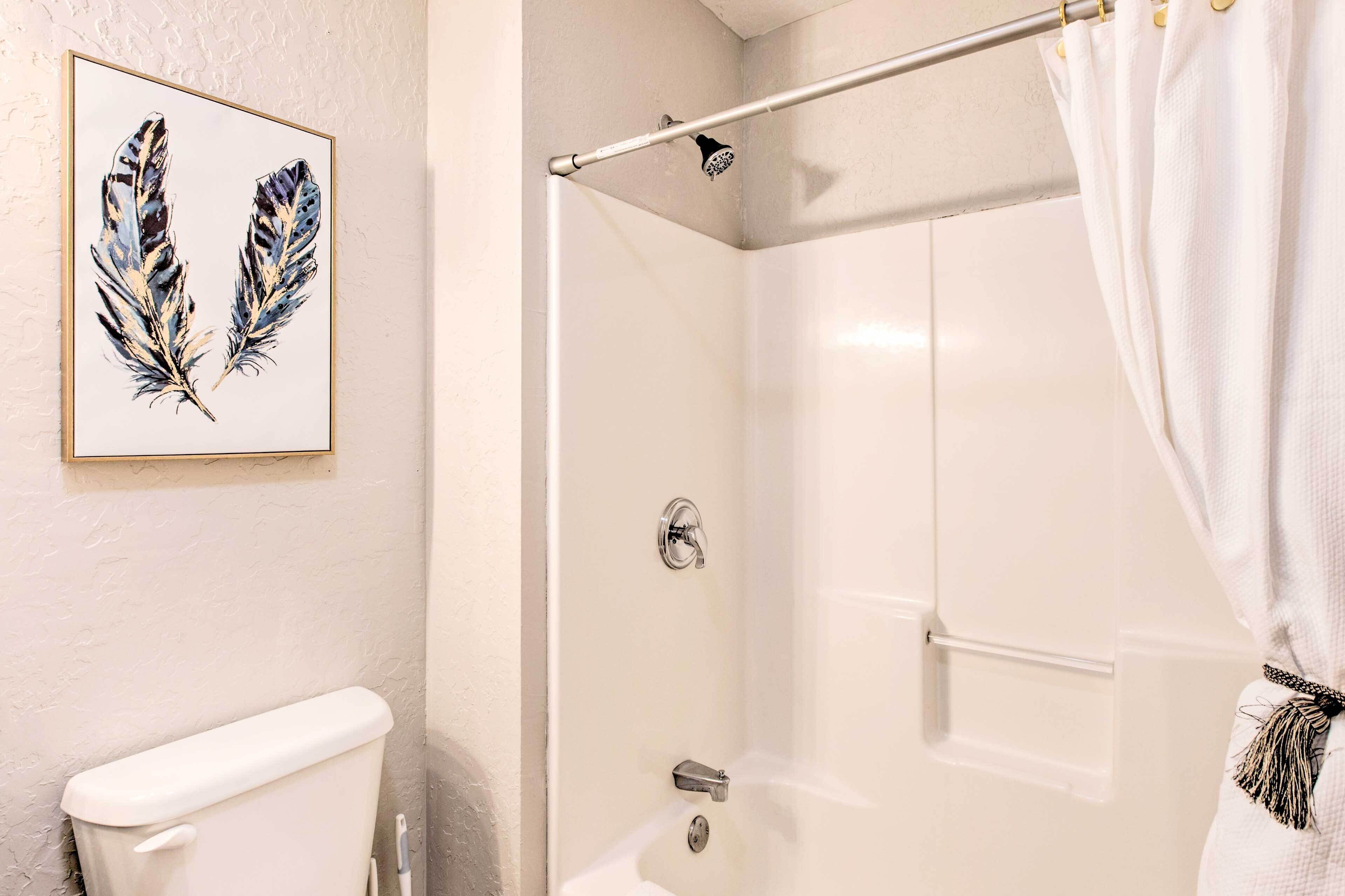 A bathroom with a toilet, a shower with a glass door, and a framed artwork on the wall.