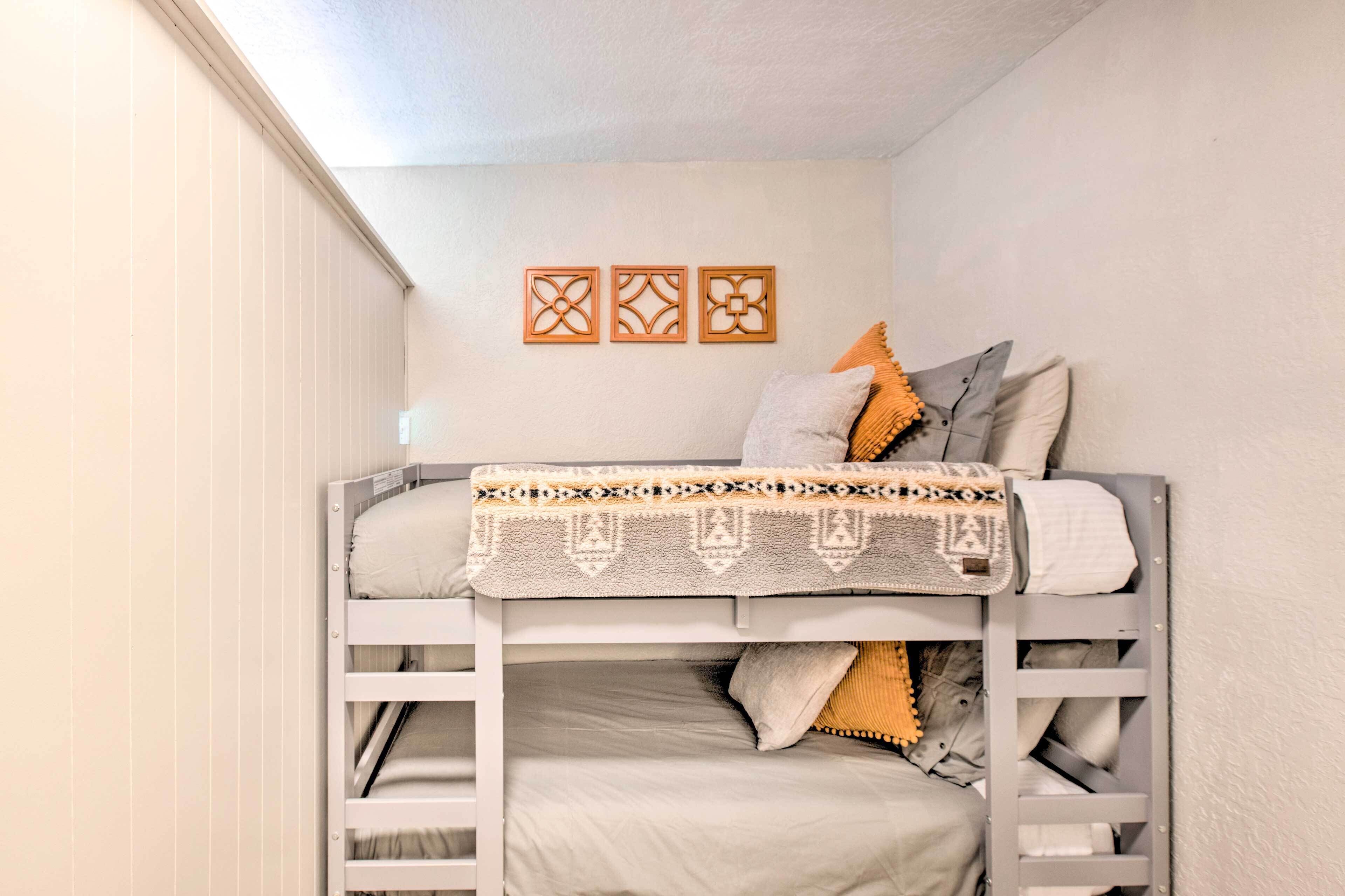 Ein Stockbett mit einem gemusterten Bettbezug, Kissen und Wandbildern.