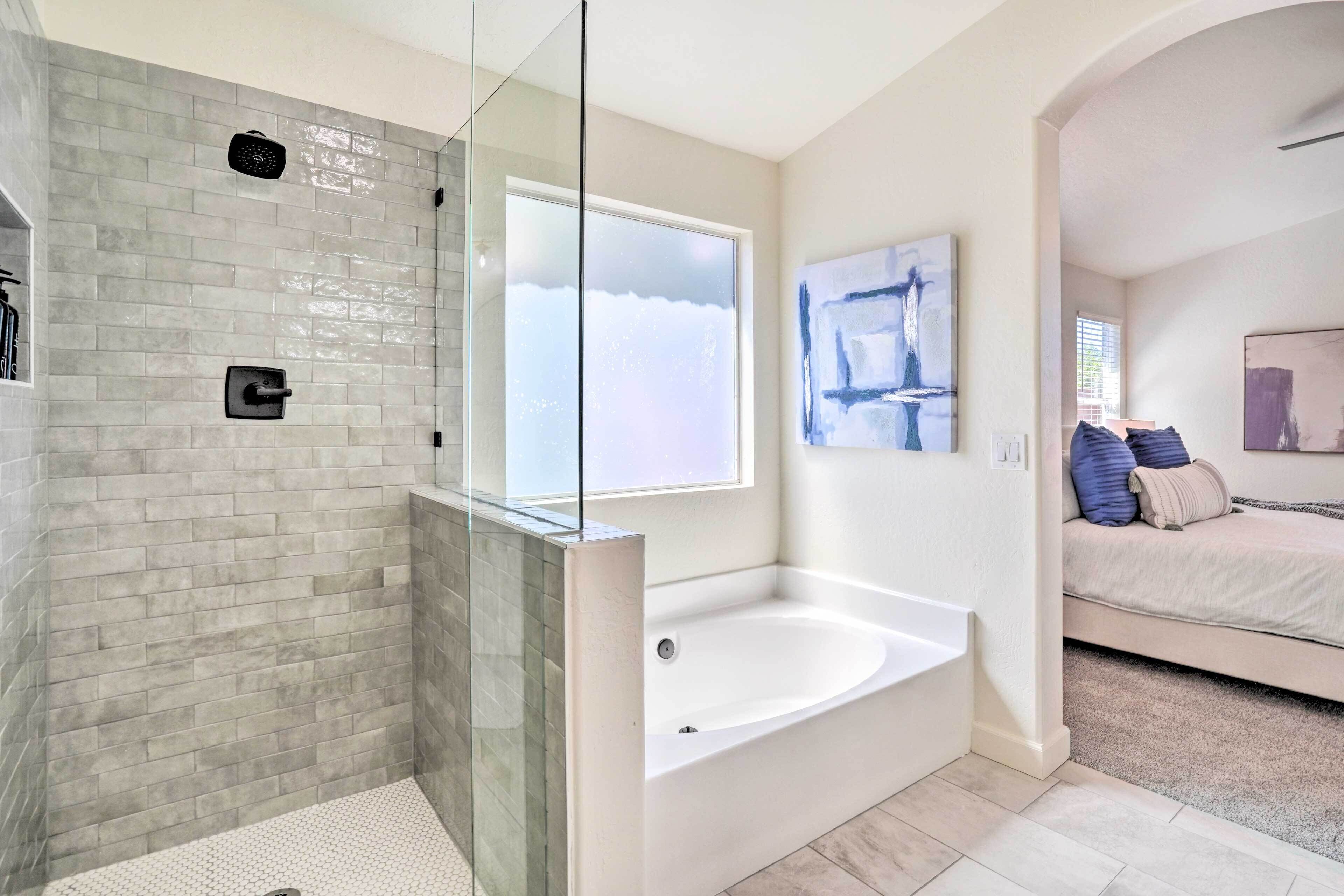 A modern bathroom with a glass-enclosed shower, a freestanding bathtub, and a large window.