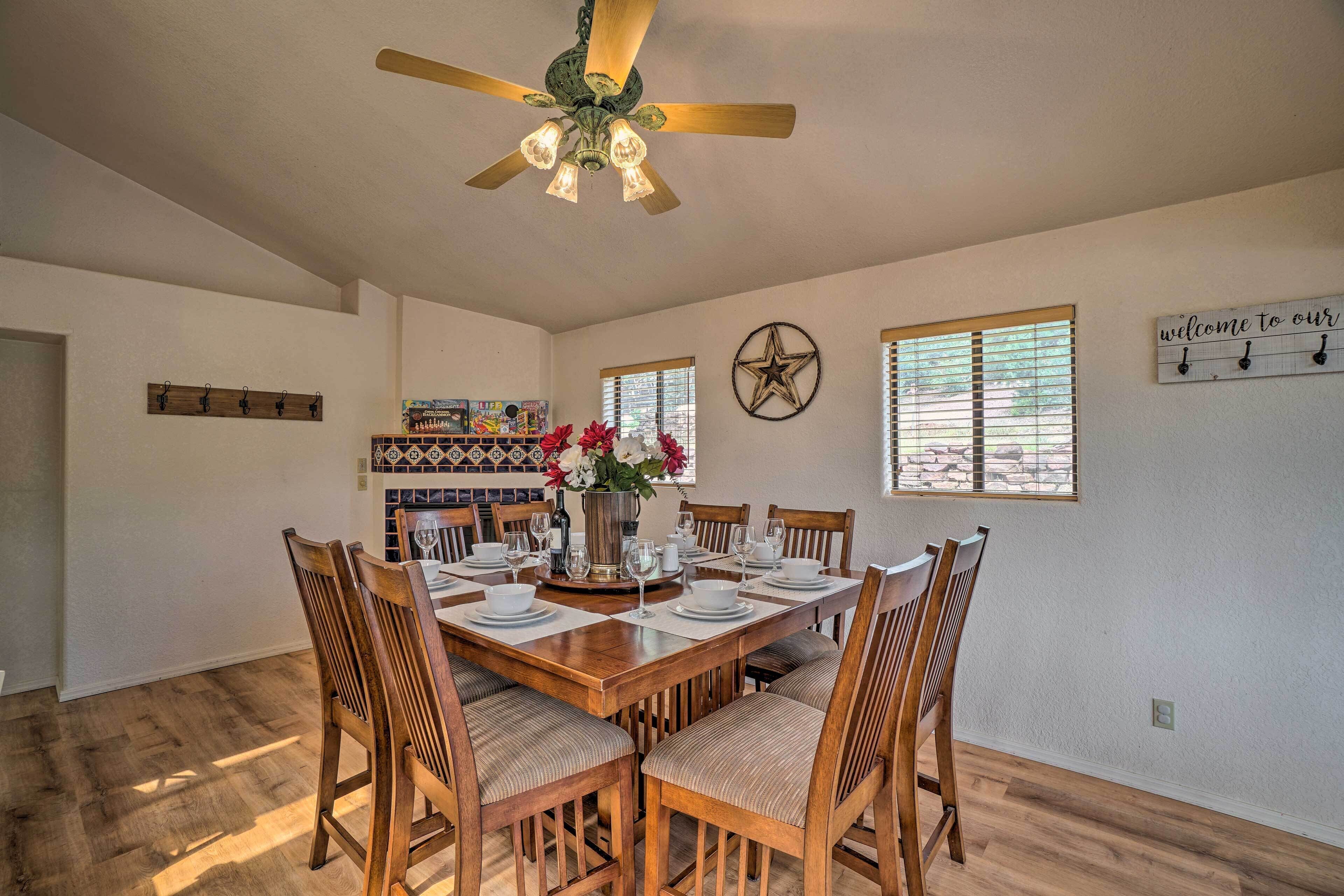 A dining area with a wooden table set for six, surrounded by chairs, a decorative wall clock, and a star-shaped wall decoration.
