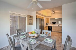 A dining area with a table set for six, a ceiling fan, and a view into the kitchen. - 3 Mi to Surprise Stadium! Retreat w/ Putting Green (Surprise)