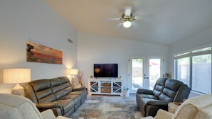 A living room with leather sofas, a flat-screen TV, and a ceiling fan. - 3 Mi to Surprise Stadium! Retreat w/ Putting Green (Surprise)
