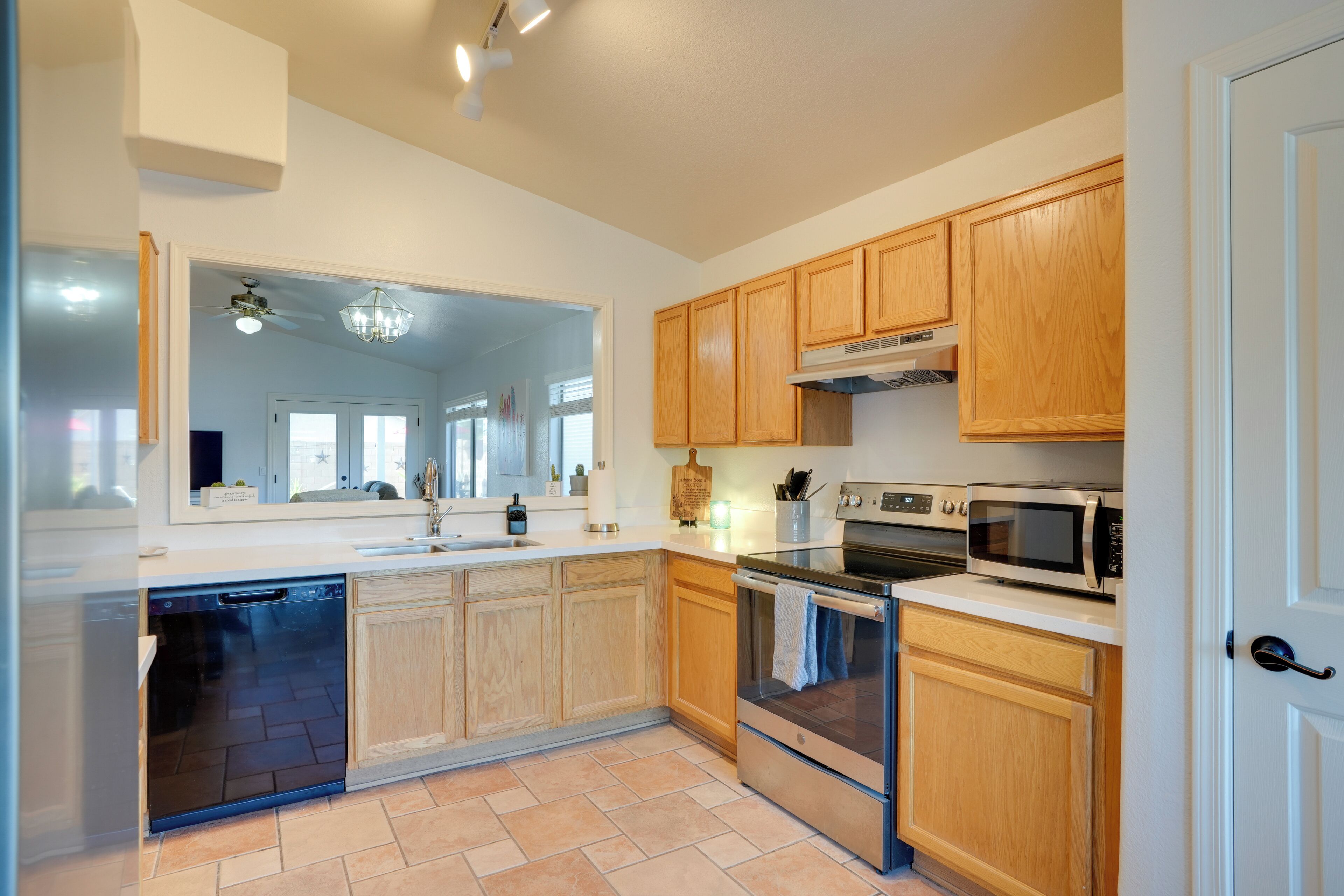 A modern kitchen with wooden cabinets, a dishwasher, an oven, and a microwave.