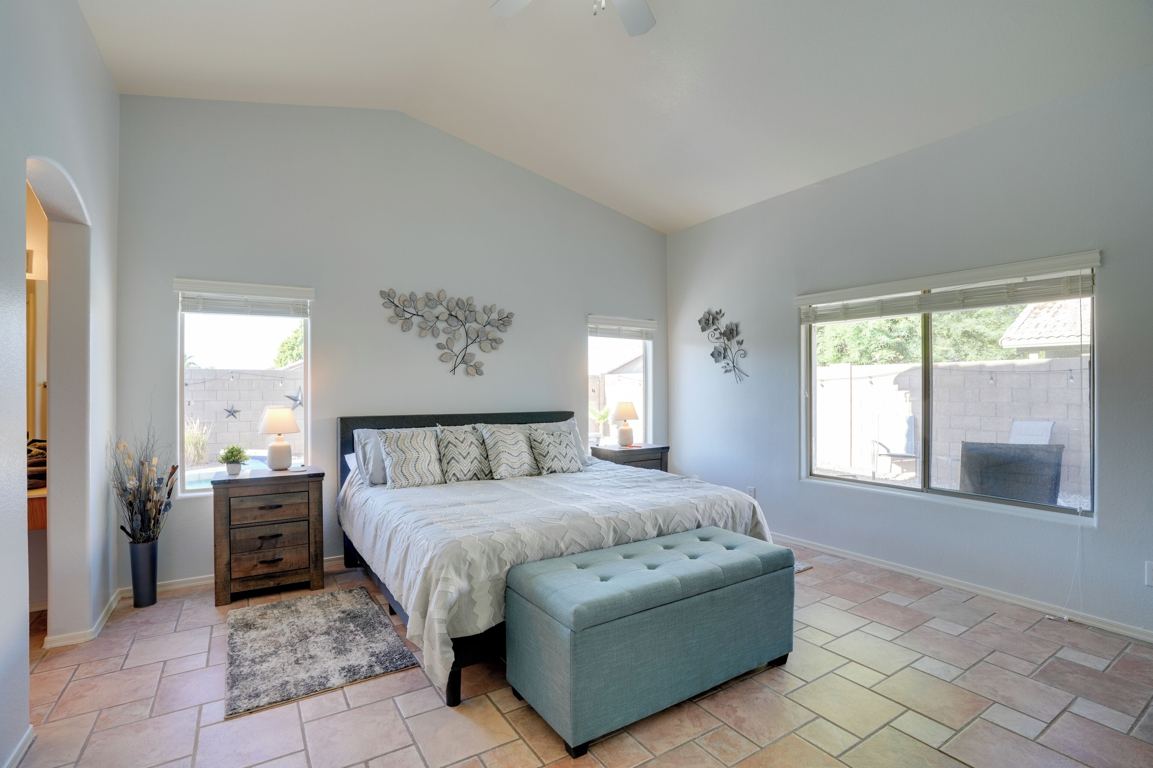 A bedroom with a bed, bedside tables, a bench, and a window.