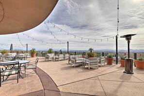 An outdoor patio with seating, potted plants, and string lights against a backdrop of a cloudy sky and distant mountains. - Catalina Mountain Studio w/ Tucson Valley Views (Tucson)
