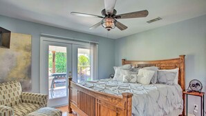 A bedroom with a wooden bed, a ceiling fan, a chair, and a view of the outdoors. - Lakefront Family Home w/ Boat Dock + Slip in Texas (Trinidad)