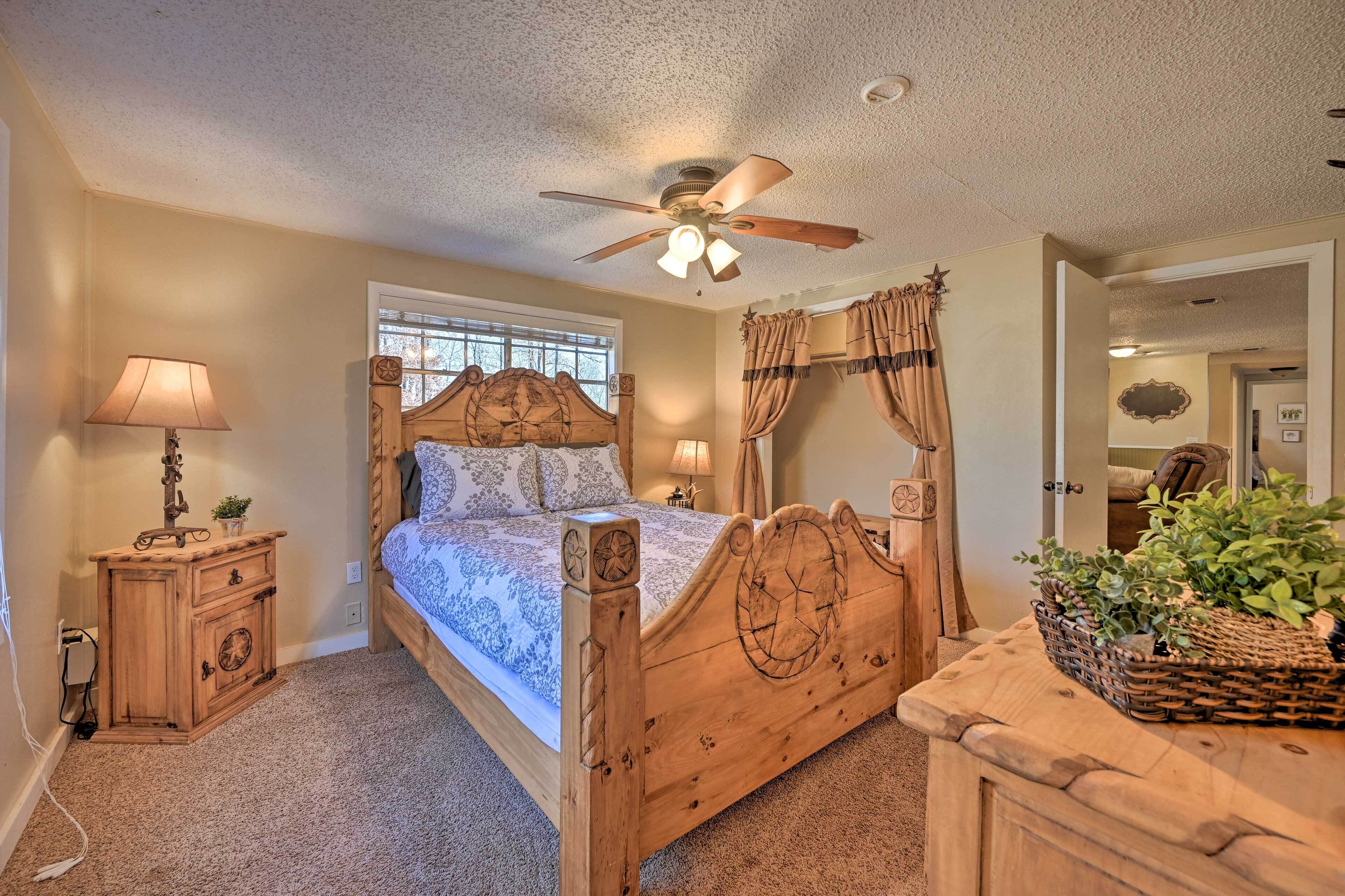 A bedroom with a wooden bed, a nightstand, a ceiling fan, and a window with curtains.