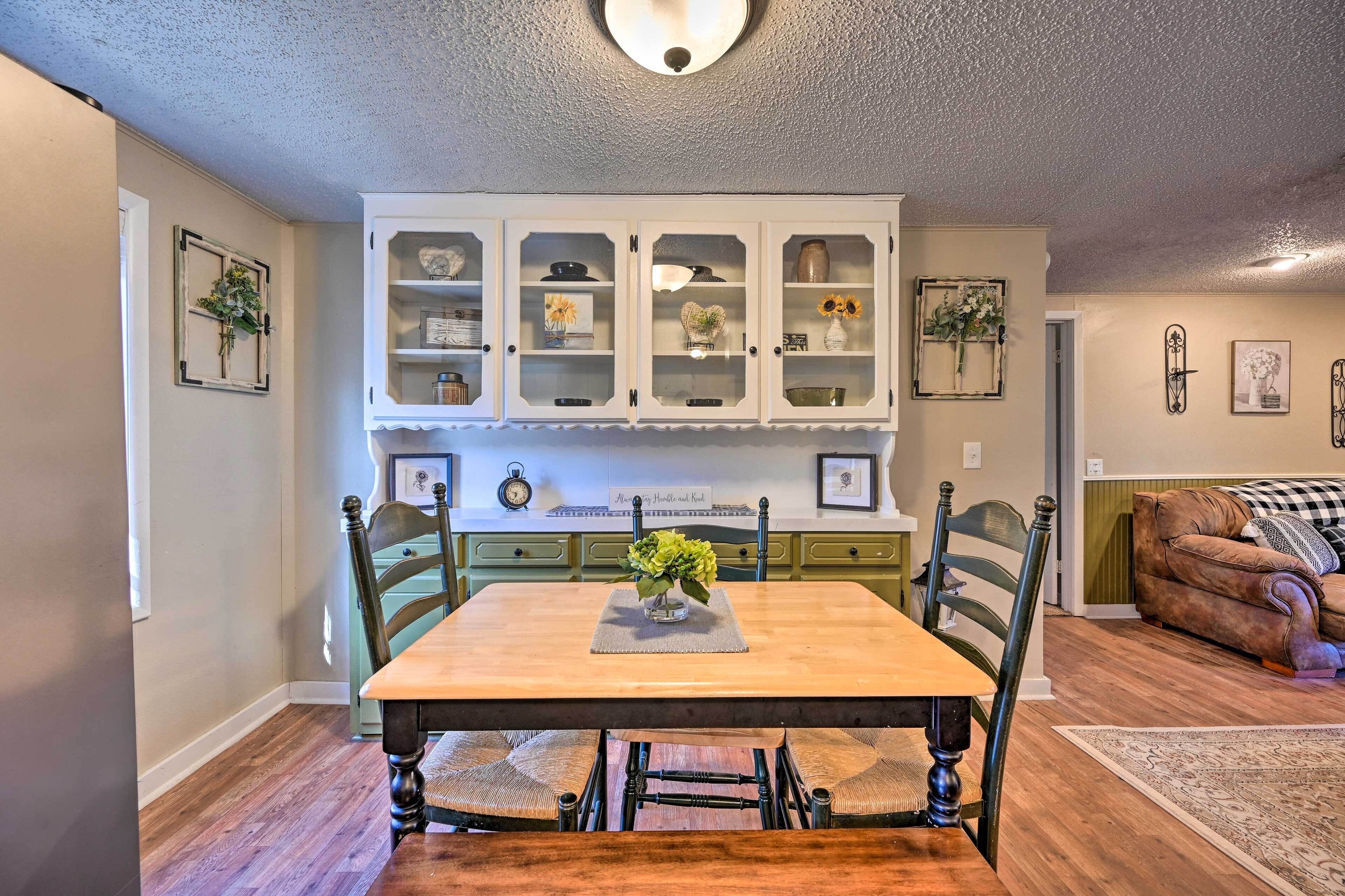 Un comedor con mesa de madera, sillas y un mueble con puertas de cristal.