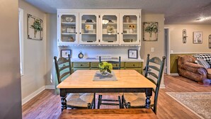 A dining area with a wooden table, chairs, and a cabinet with glass doors. - 'whispering Oaks' Broken Bow Cottage Near Hiking! (Broken Bow)