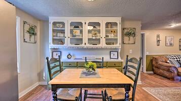 Un comedor con mesa de madera, sillas y un mueble con puertas de cristal.