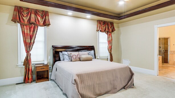 A bedroom with a large bed, two nightstands, and a window with curtains.