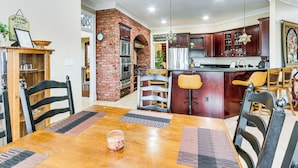 A spacious kitchen with a brick accent wall, wooden cabinetry, and a central island.