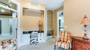 A room with a desk, chair, dresser, and a lamp.