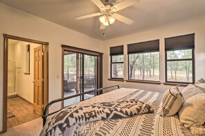 Un dormitorio con cama, ventilador de techo y ventanas amplias con persianas.
