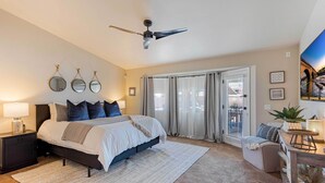 A bedroom with a bed, bedside tables, a ceiling fan, and a view of a bridge through the window.