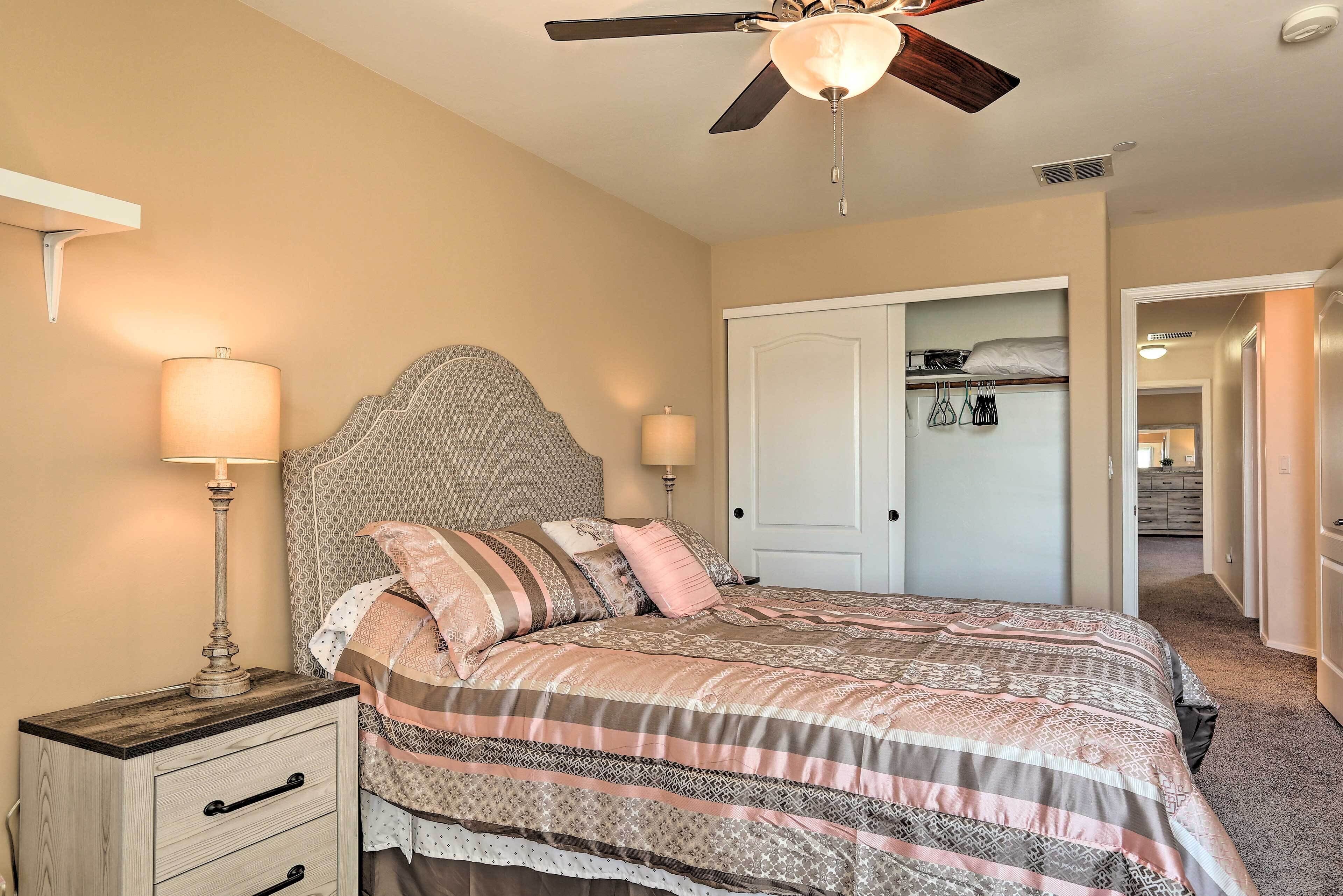 A bedroom with a bed, nightstands, a ceiling fan, and a wardrobe.