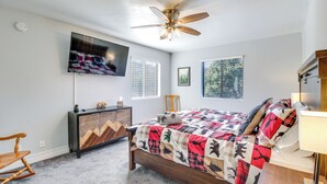 A bedroom with a bed, a ceiling fan, a TV, a dresser, a rocking chair, and windows with blinds. - Eagar Vacation Rental Home w/ Spacious Deck! (Eagar)