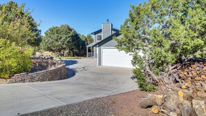 A residential driveway leading to a house with a garage, surrounded by trees and a stone wall. - Eagar Vacation Rental Home w/ Spacious Deck! (Eagar)