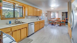 A kitchen with wooden cabinets, a stainless steel sink, and a dining area with wooden chairs and a table. - Eagar Vacation Rental Home w/ Spacious Deck! (Eagar)