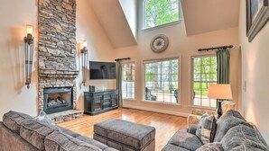 A spacious living room with a stone fireplace, a large sectional sofa, and a flat-screen TV.