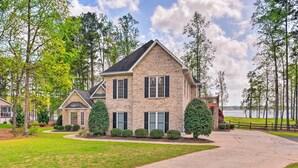 A two-story house with a brick exterior, a driveway, and a lake view.