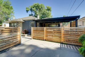 Propiedad residencial con valla de madera, patio cubierto y una casa con garaje.