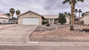 A residential house with a garage, palm trees, and a gravel driveway.