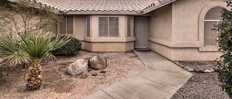 A stucco house with a tiled roof, a front door, and a small porch area.