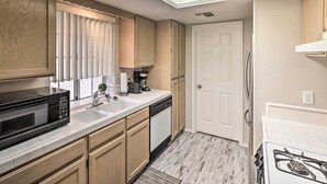 A kitchen with wooden cabinets, a microwave, a coffee maker, and a dishwasher.
