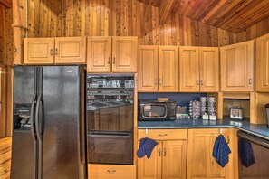 Una cocina con armarios de madera, refrigerador, horno, microondas y tostadora.