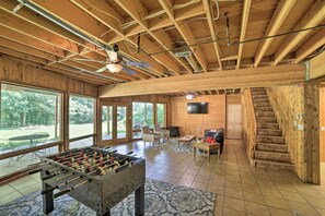 Una habitación amplia con mesa de futbolín, televisión y una escalera.