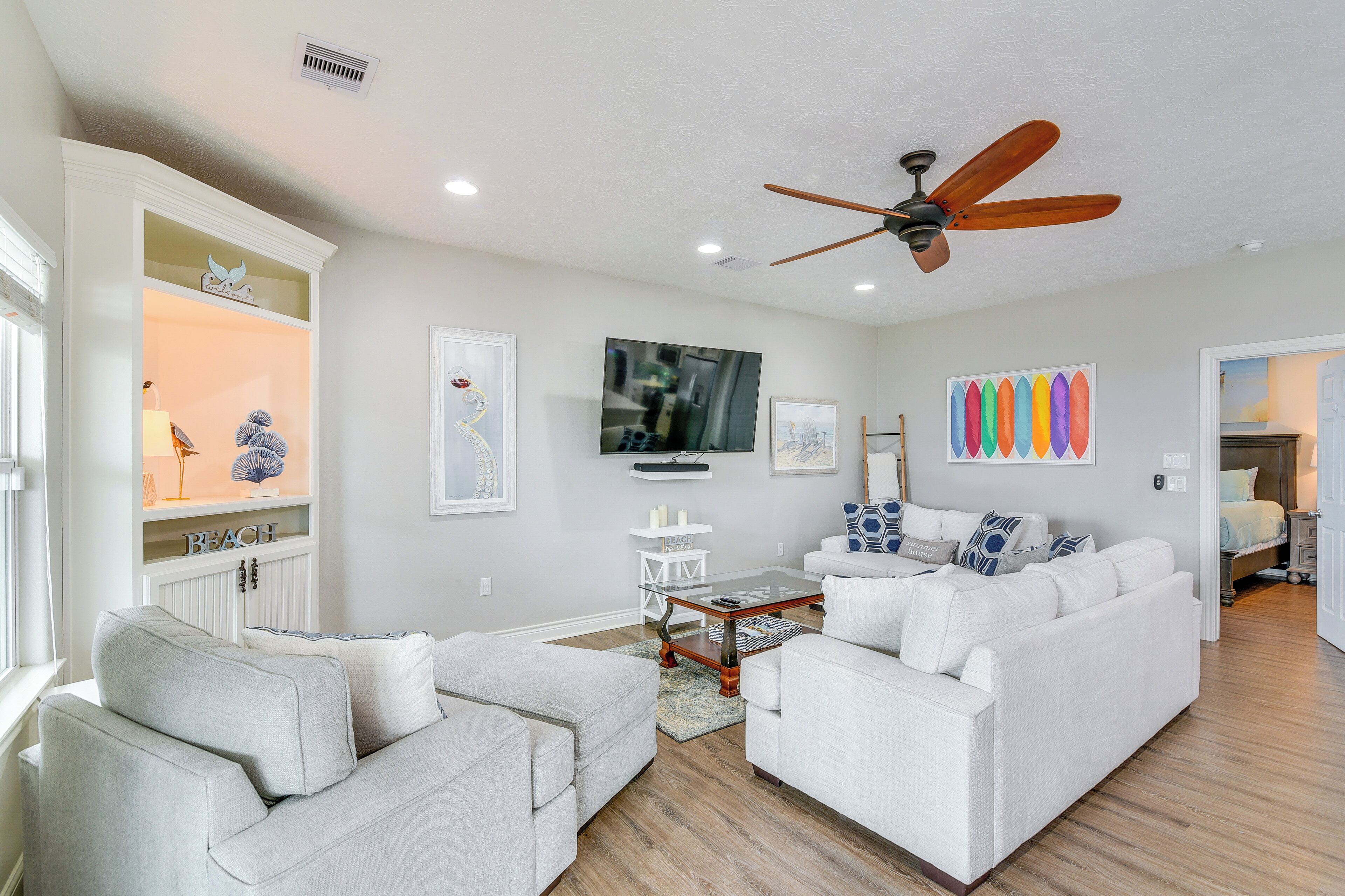 A modern living room with a white sofa set, a coffee table, and a ceiling fan.