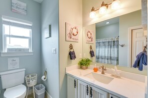 Bathroom features a toilet, sink, and window with blinds, along with a towel rack and toiletries.