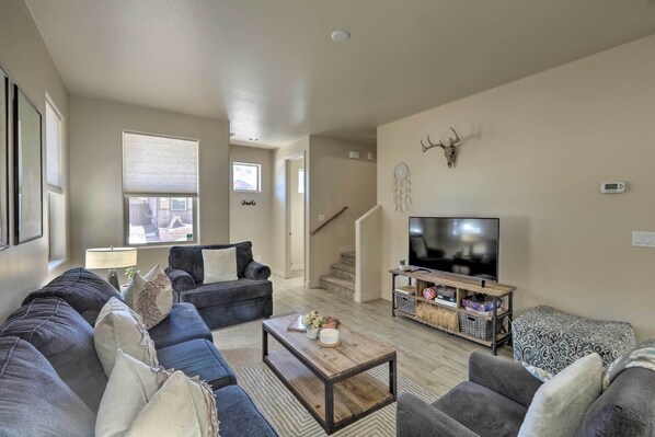 A living room with a sofa set, a coffee table, a TV, and a staircase leading to another level.