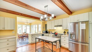 A spacious kitchen with wooden beams, a stainless steel refrigerator, and a dining area with a table and chairs. - 15 Mi to Gloucester: Waterfront Mathews Home! (Mathews)