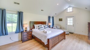 A spacious bedroom with a large bed, wooden headboard, and a view of the outdoors through a window. - 15 Mi to Gloucester: Waterfront Mathews Home! (Mathews)