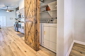 A kitchen with wooden flooring, white cabinets, a built-in oven, and a ceiling fan.