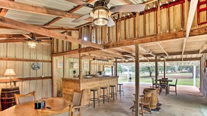 Un intérieur rustique en bois, avec un coin bar, de hauts plafonds et une vue sur l’extérieur.