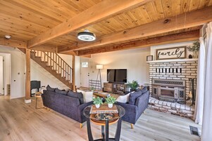 Un salón amplio con chimenea, vigas de madera en el techo y una zona de estar acogedora.