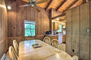 Comedor de madera con una mesa, sillas, una ventana con persianas y un ventilador de techo.