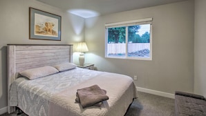A bedroom with a large bed, a nightstand with a lamp, a framed picture on the wall, and a window with a view of trees and a fence. - 1 Mi to Winery: Clifton Escape w/ Grill & Yard! (Clifton)