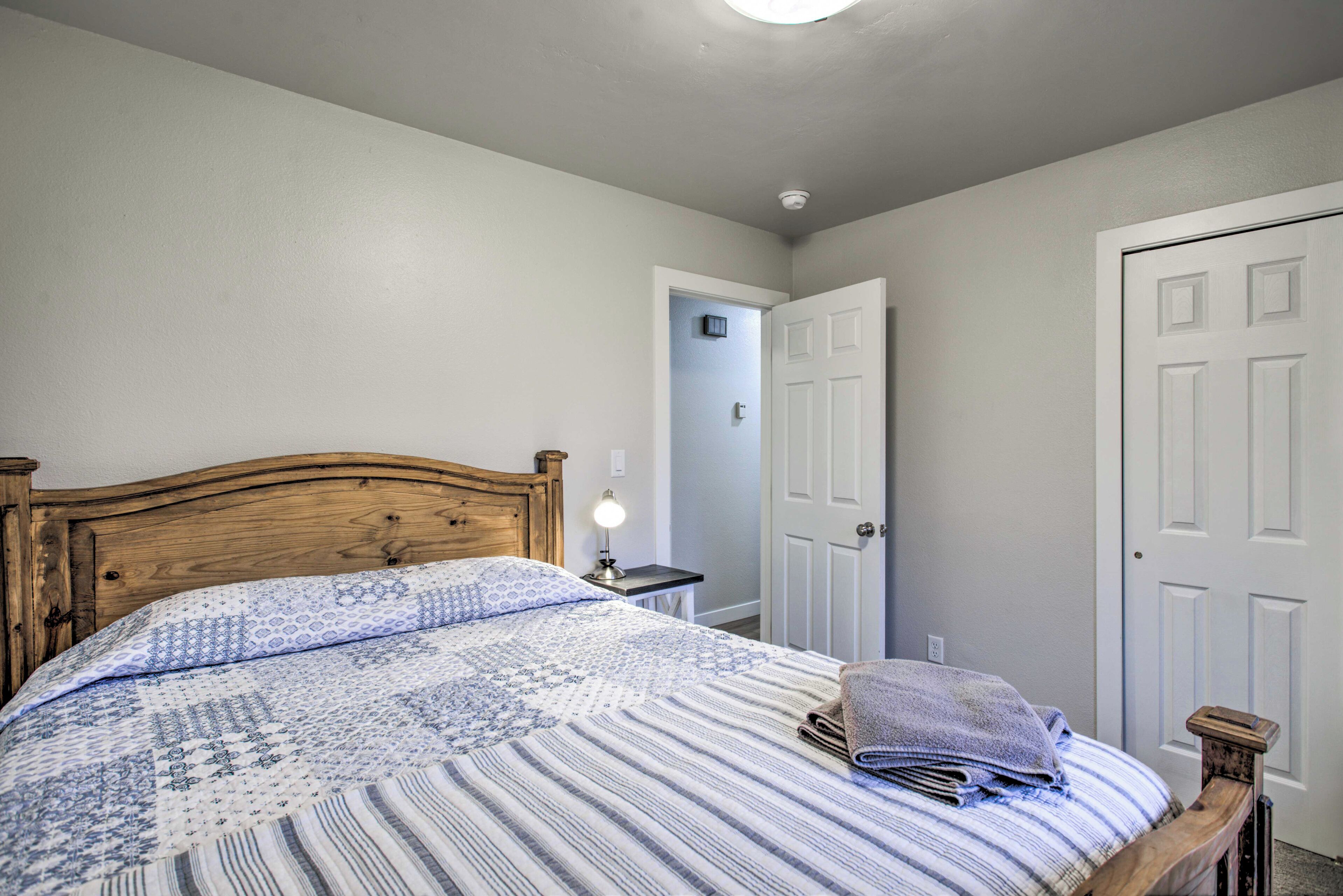 A bedroom with a wooden headboard, a patterned bedspread, and a folded towel on the bed.