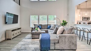 A spacious living room with a sectional sofa, a flat-screen TV, and a dining area with bar stools. - Chic Houston Home w/ Game Room ~ 8 Mi to Dtwn (Houston)