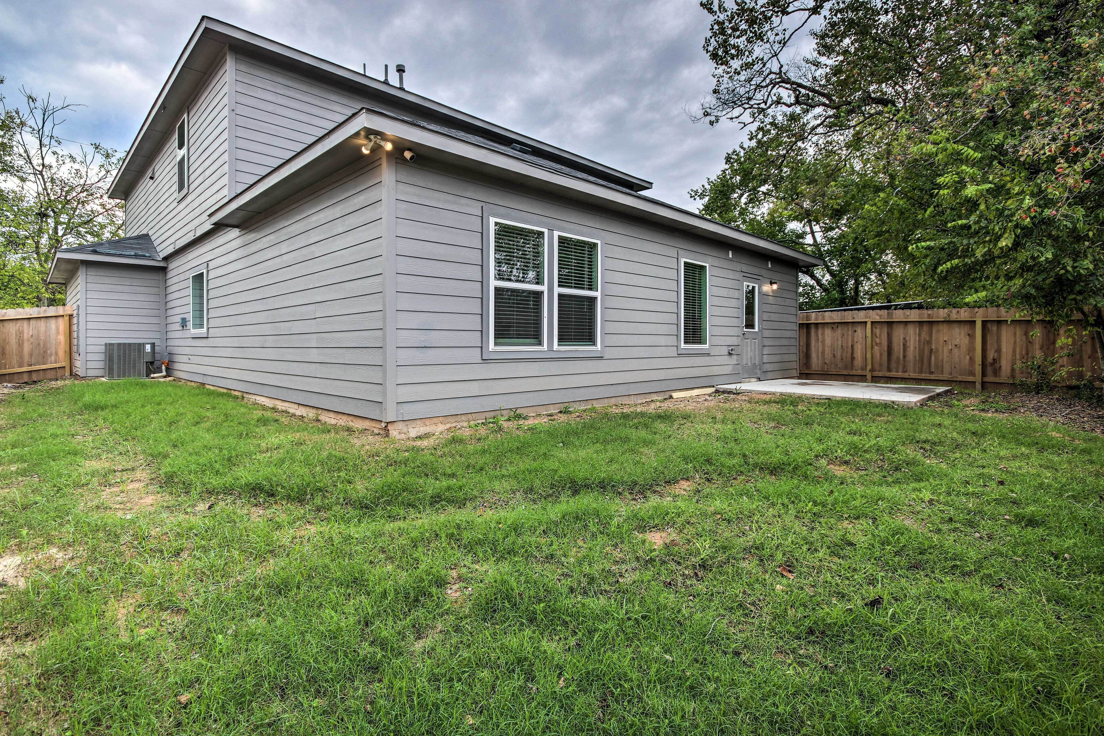 A two-story house with a covered porch, a fenced backyard, and a wooden deck.
