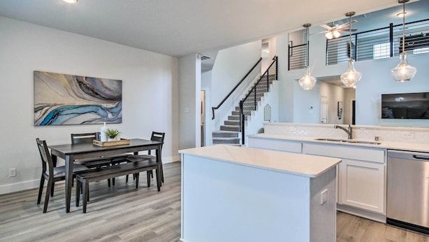 A modern kitchen with a central island, a dining area with dark wood furniture, and a staircase leading to an upper level. - Chic Houston Home w/ Game Room ~ 8 Mi to Dtwn (Houston)