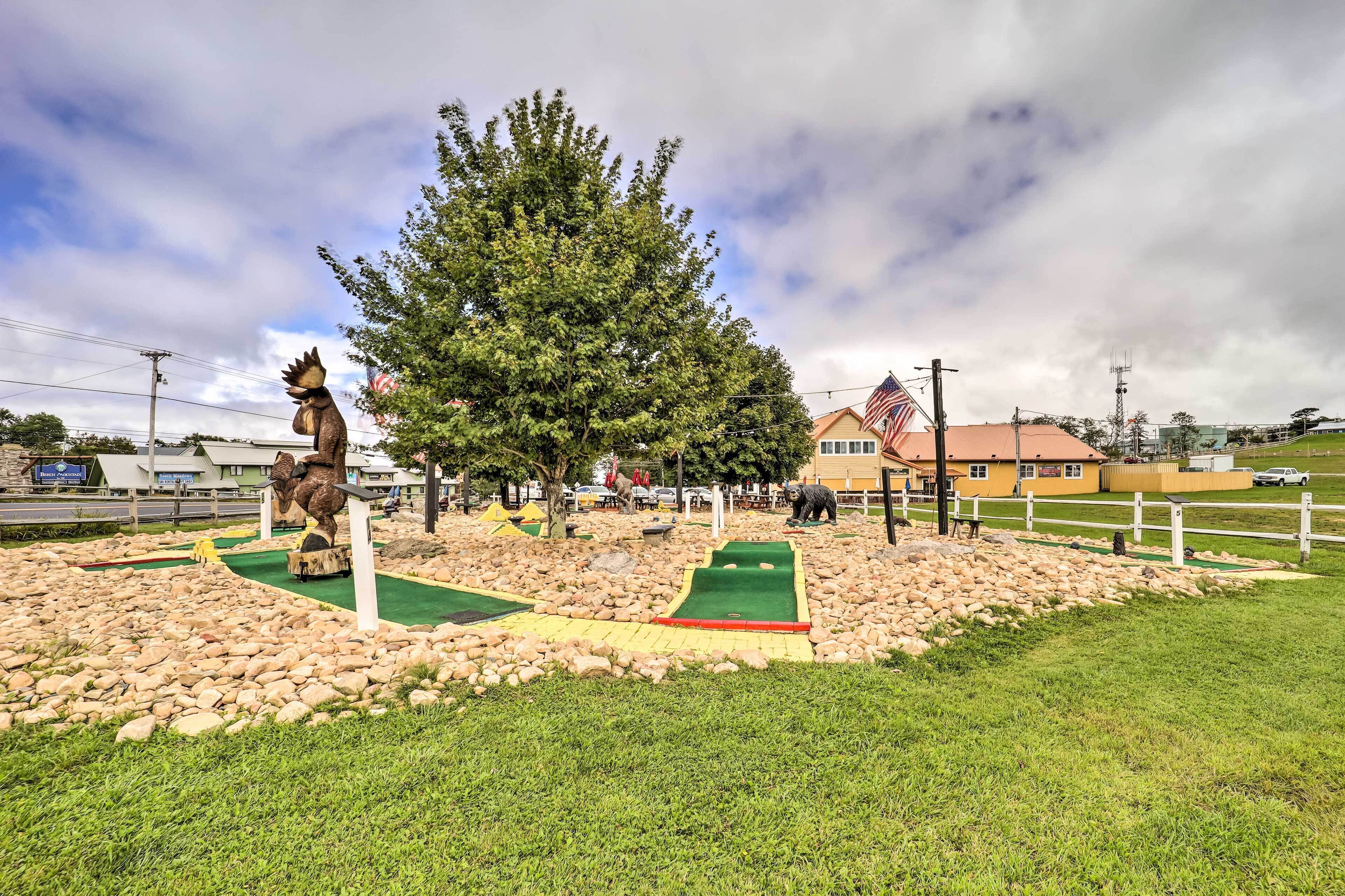 A golf course with a putting green, a large tree, and a statue.