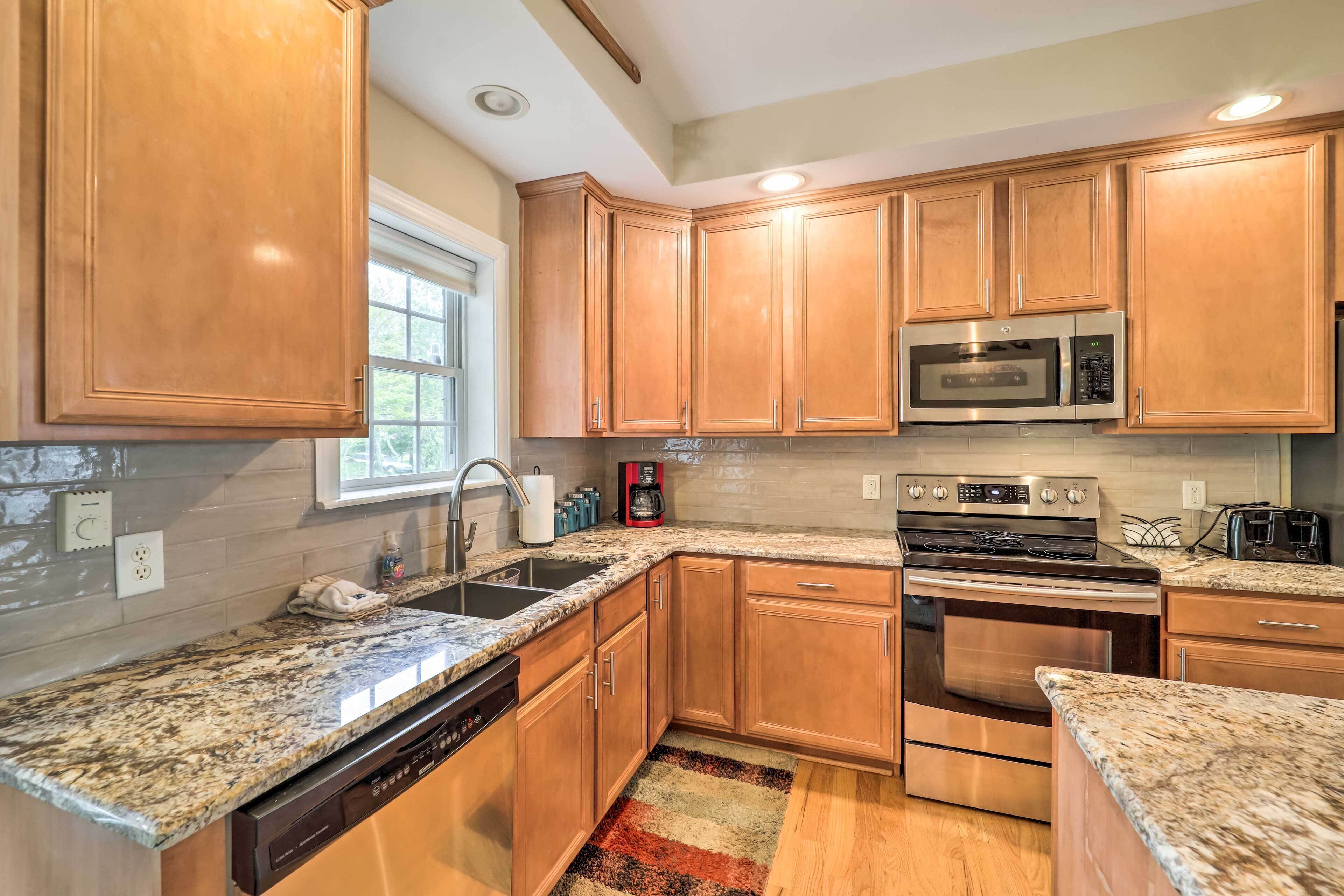 A kitchen with wooden cabinets, granite countertops, a stainless steel oven, and a microwave.
