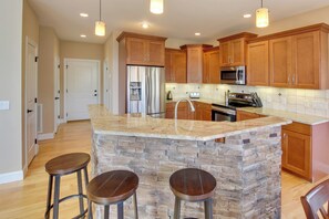 A kitchen with wooden cabinets, a stone island, and a stainless steel refrigerator. - Stunning Nebo Lake House w/ Deck & Views! (Nebo)